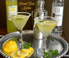 two martinis on a silver tray with lemon slices