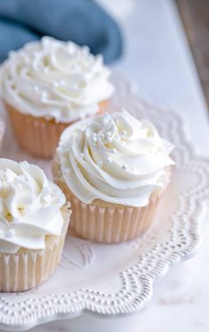 four cupcakes with white frosting on a plate