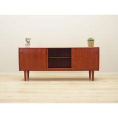 a wooden sideboard with two plants on top and one potted plant next to it