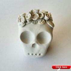 a white skull with flowers on it's head sitting on top of a table