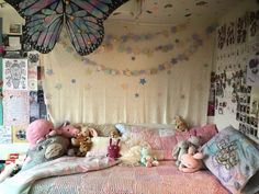 a bed with lots of stuffed animals on it and a butterfly hanging from the ceiling