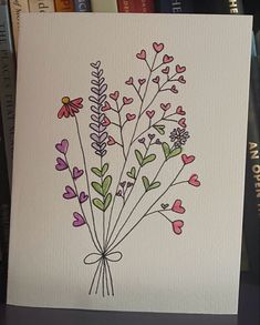 a card with flowers and hearts drawn on it in front of some bookshelves