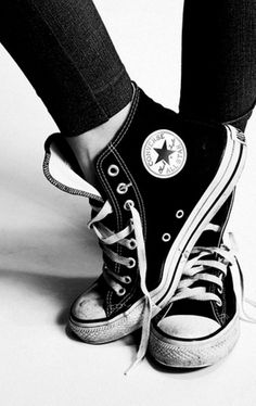 black and white photograph of someone's feet wearing converse sneakers