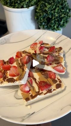 three pieces of cake on a plate with chocolate, strawberries and cream toppings