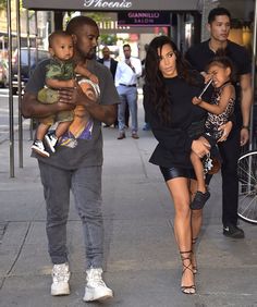 the couple are walking down the street with their two children on their shoulders and one baby in his arms