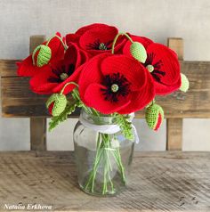 a vase filled with red flowers on top of a wooden table