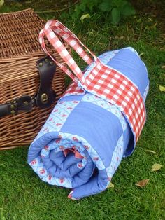 two pieces of luggage sitting on the grass next to each other in front of a wicker basket