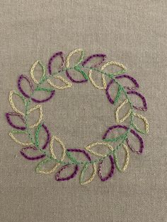 a close up of a piece of cloth with embroidery on it and a circle made out of leaves