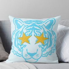 a blue and white tiger pillow sitting on top of a couch next to two pillows