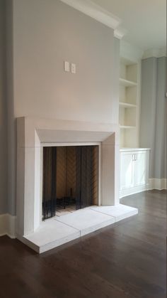 an empty living room with a fireplace and built - in bookcases