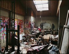 a room filled with lots of clutter next to a wall covered in paintings and artwork