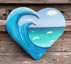 a painted heart shaped like a wave on a wooden fence with blue sky and clouds in the background