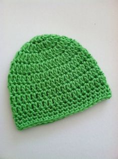 a green knitted hat sitting on top of a white table