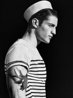 a man with a sailor's cap on his head and tattoos on his arm