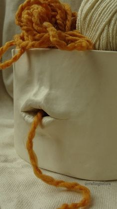 a ball of yarn is in the shape of a white face with orange hair on it