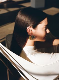 a woman with long black hair is looking at her cell phone while sitting in a chair