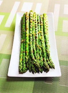 asparagus on a white plate sitting on a green and white checkered tablecloth