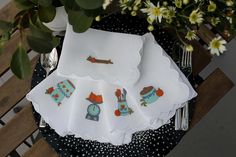 four napkins on a table with flowers in the background