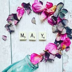 the word may spelled with scrabbles and pink flowers on a white wooden background