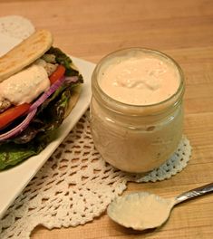 a plate with a sandwich on it next to a jar of dressing