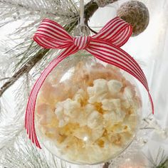 a glass ornament hanging from a christmas tree with candy and bows on it