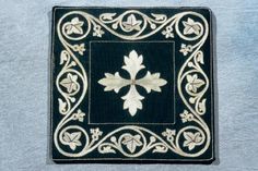 a black and white square with an ornate design on the center, surrounded by flowers