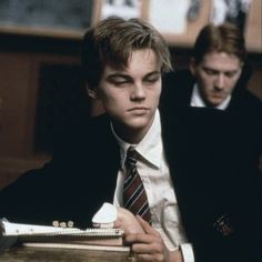 two young men in suits and ties sitting at a table with an old typewriter