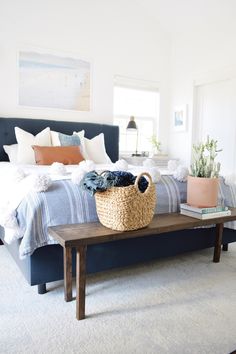 a bedroom with a large bed and a basket on the coffee table in front of it