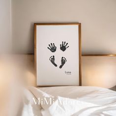 an image of a baby's hand and foot prints on a white wall above a bed