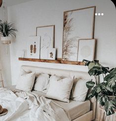 a bed with white sheets, pillows and pictures on the wall above it in a bedroom