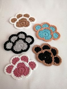 four crocheted paw prints on a white surface