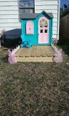 a doll house made out of pallets in the yard with pink doors and windows