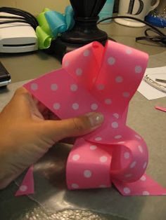 a hand is holding a pink bow on a table