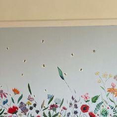 a painted mural on the side of a wall with flowers and bees flying over it