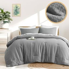 a bed in a bedroom with grey comforter and pillows