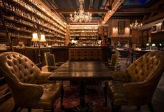 a bar with several chairs around a table and chandelier hanging from the ceiling