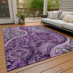 a purple and black rug on a wooden floor in front of a porch with couches