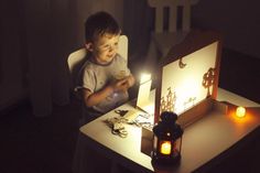 a young boy sitting in front of a desk with a lit up mirror on it