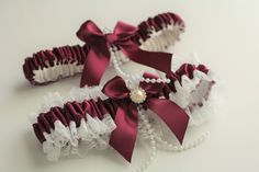 two garters with pearls and ribbons on them sitting next to eachother