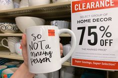 a person holding up a coffee mug in front of a store sign that says, so not a morning person 75 % off the marked price