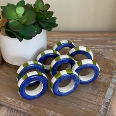 four blue and green rings sitting on top of a wooden table next to a potted plant