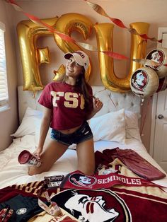 a woman sitting on top of a bed next to balloons