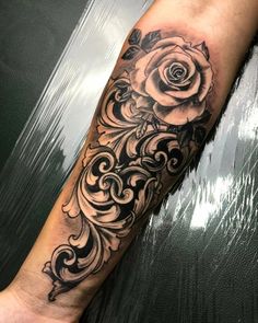 a black and white rose tattoo on the left arm, with swirls around it