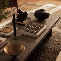 a coffee table with books and a vase on it in the middle of a living room