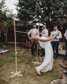 a woman in white dress standing on top of a wooden pole next to other people