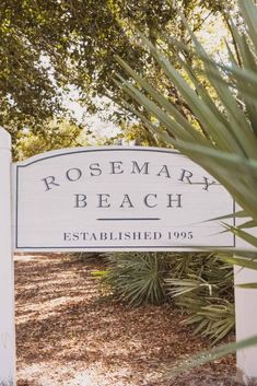 the sign for rosemary beach is shown in front of some trees and bushes with leaves