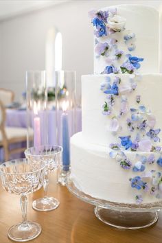 a wedding cake with blue and white flowers on it sitting on top of a table