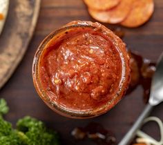 a jar filled with sauce sitting on top of a table next to vegetables and crackers