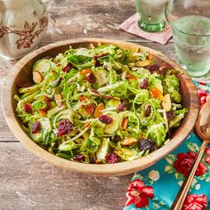 a salad in a wooden bowl with cranberries and almonds on the side