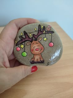 a hand holding a rock with a reindeer painted on it